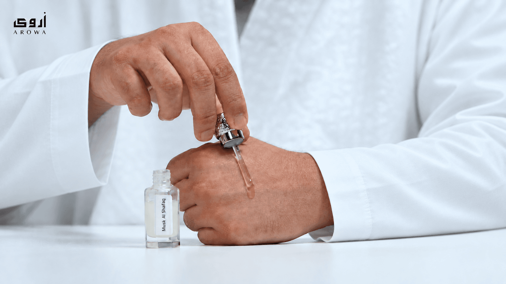 A person applying AROWA attar near the wrist